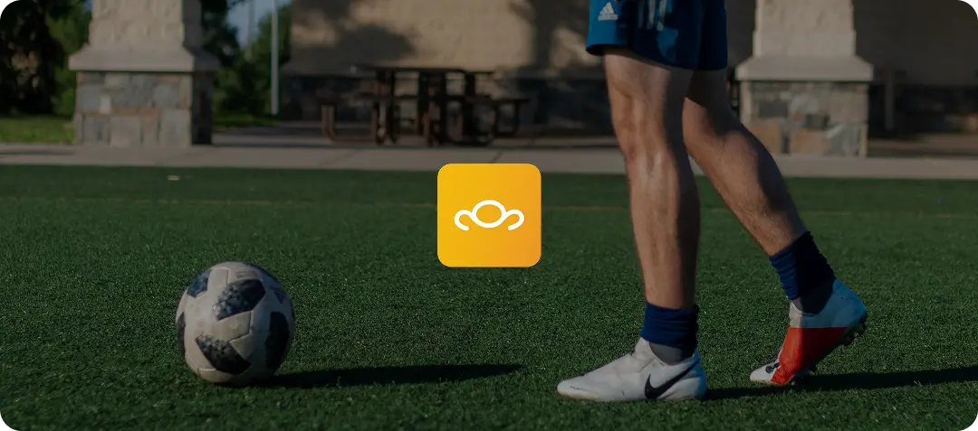 Soccer player's legs with ball on turf field and central yellow logo